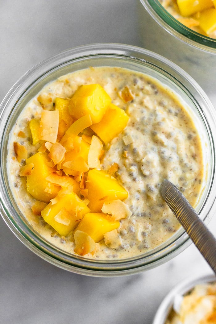Overhead shot of a jar filled with healthy overnight oats topped with mango and coconut.