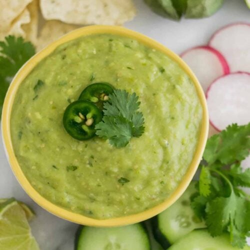 Bowl of Roasted Tomatillo Avocado Salsa surrounded by chips and veggies
