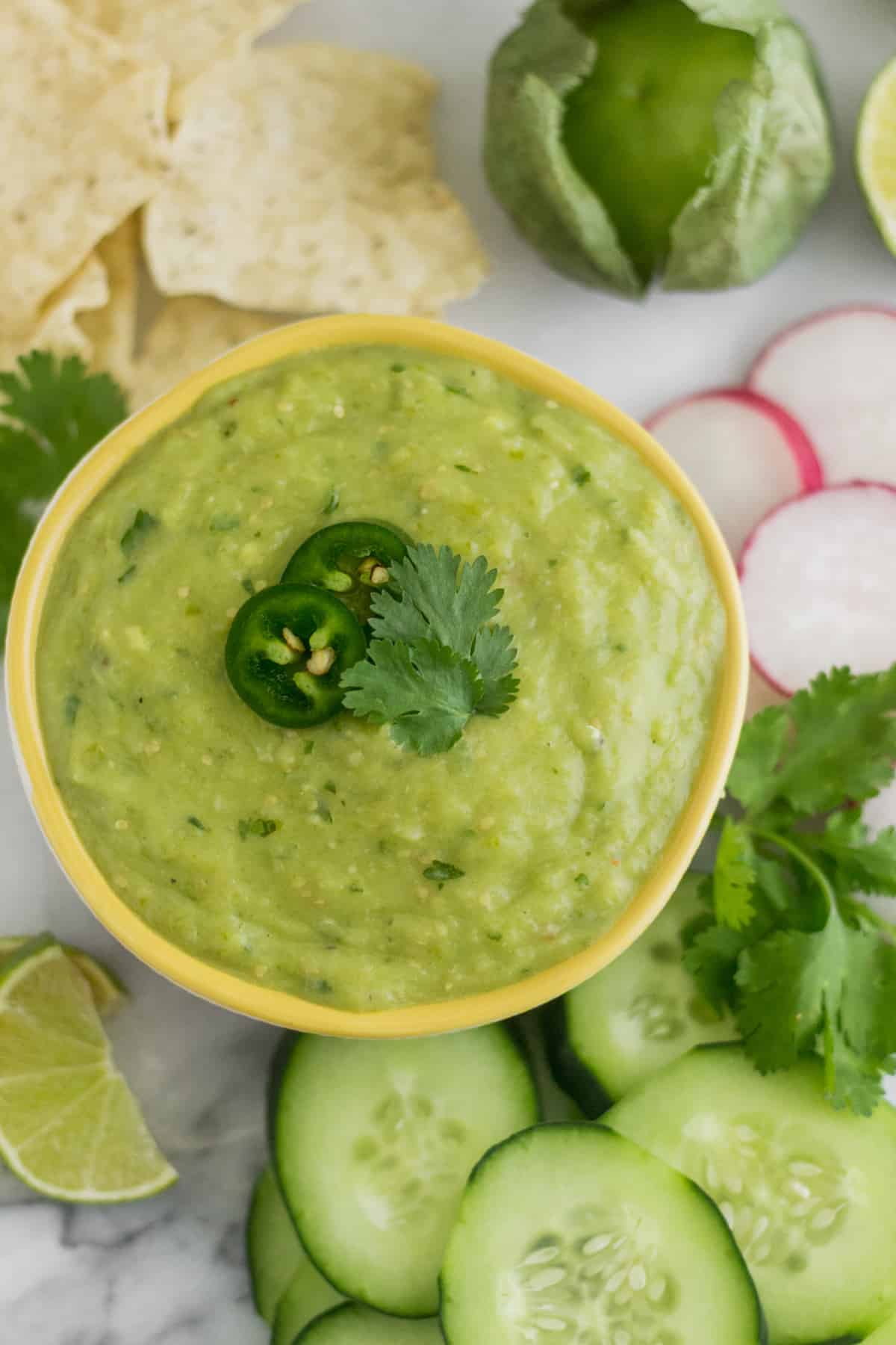 Bowl of Roasted Tomatillo Avocado Salsa surrounded by chips and veggies