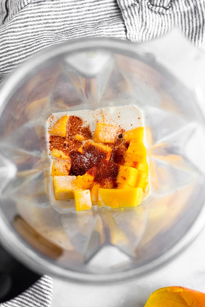 Blender filled with diced mango, coconut milk, chipotle powder, lime juice, and salt.