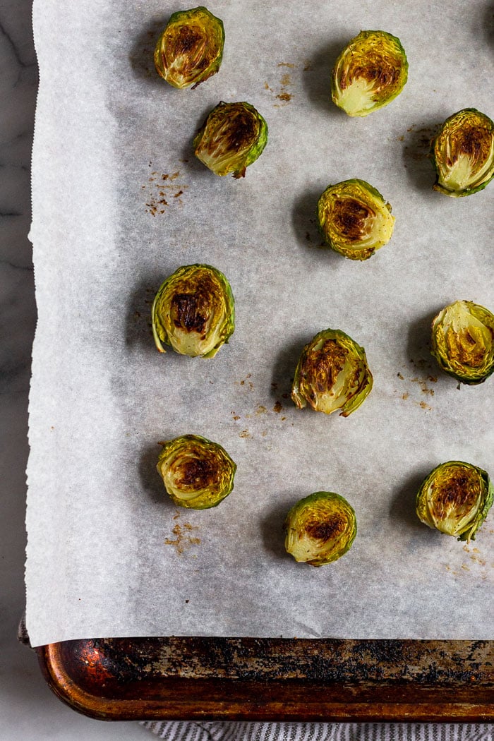 Roasted brussel sprouts on a baking sheet lined with parchment paper.