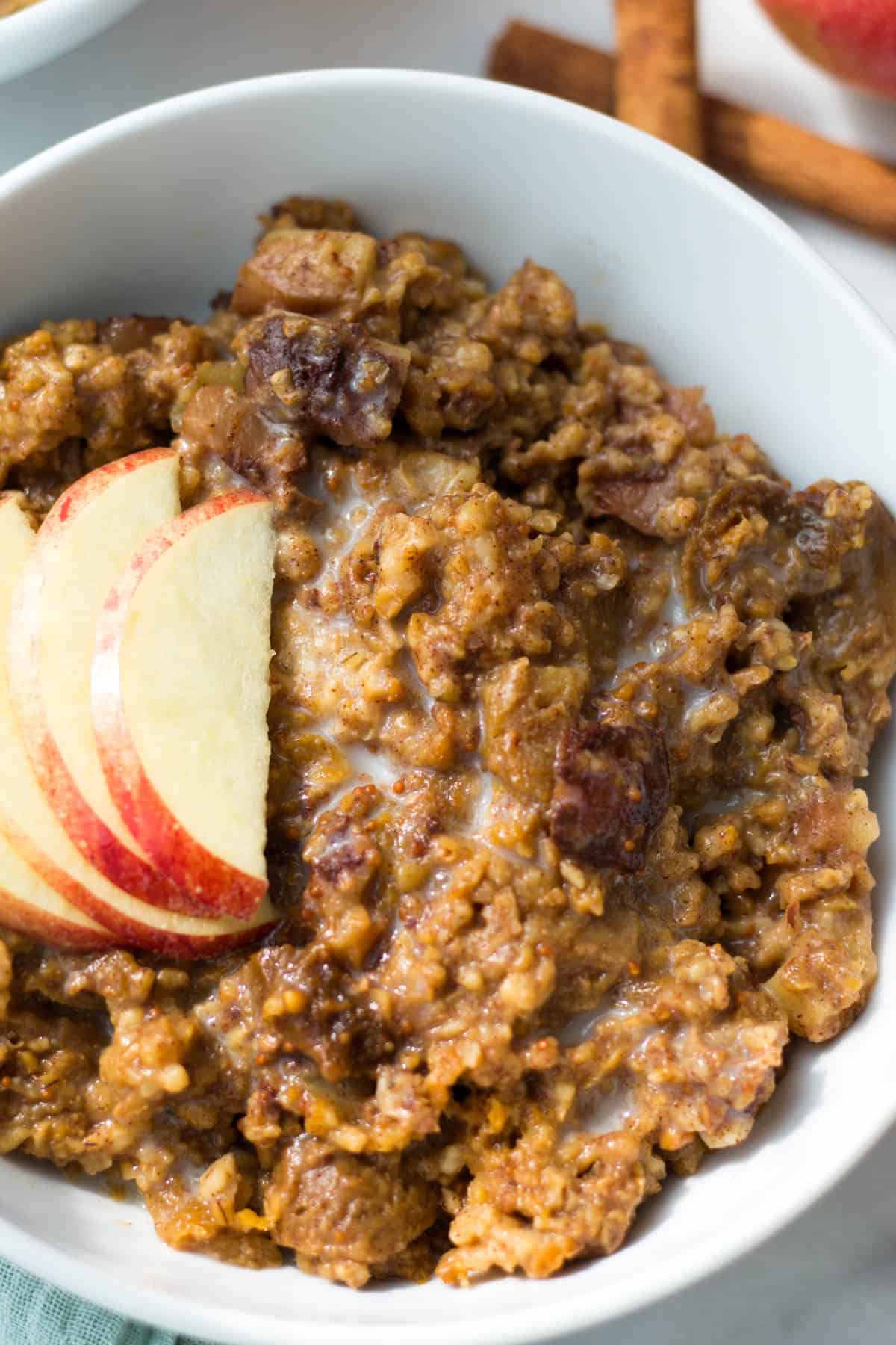 A bowl of fig apple cinnamon slow cooker steel cut oats topped with sliced apple and almond milk