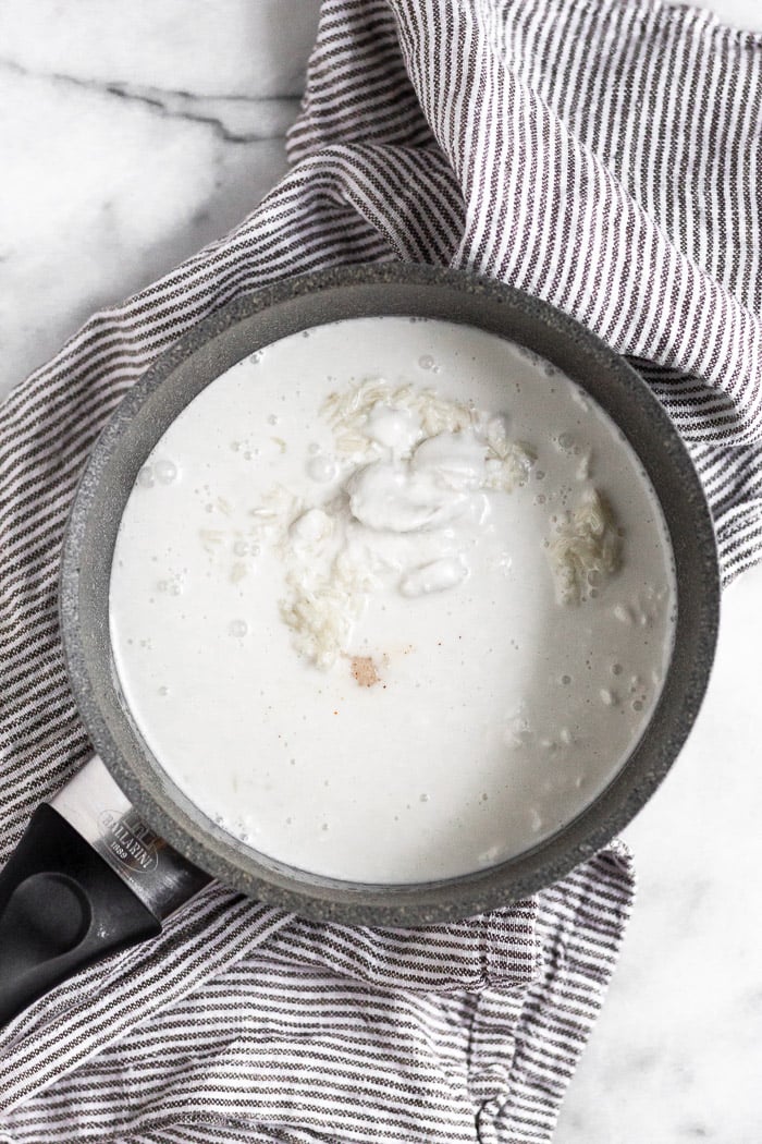 Small sauce pot filled with uncooked rice, full fat coconut milk, and a little sauce.