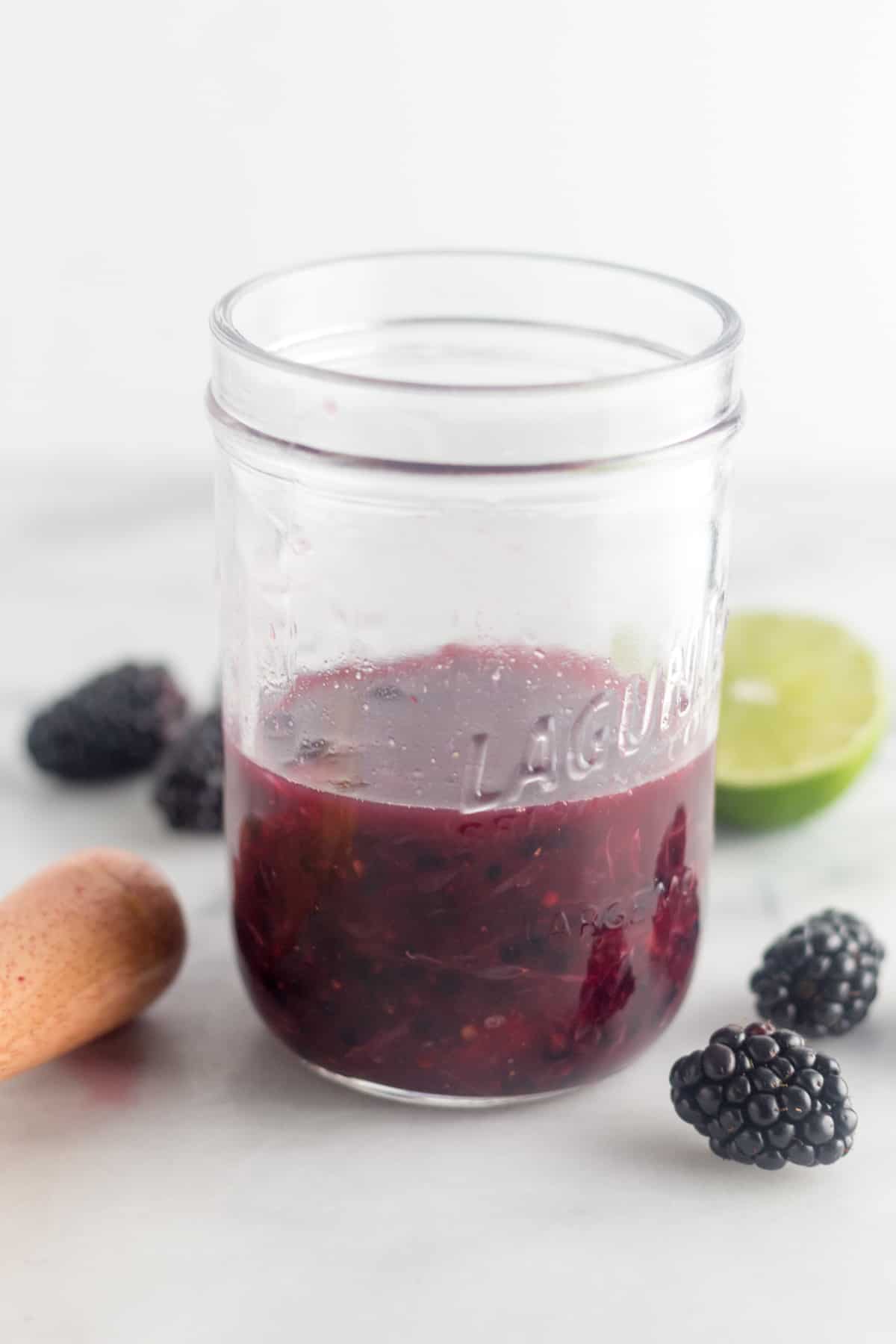 Jar of lime juice and muddled blackberries