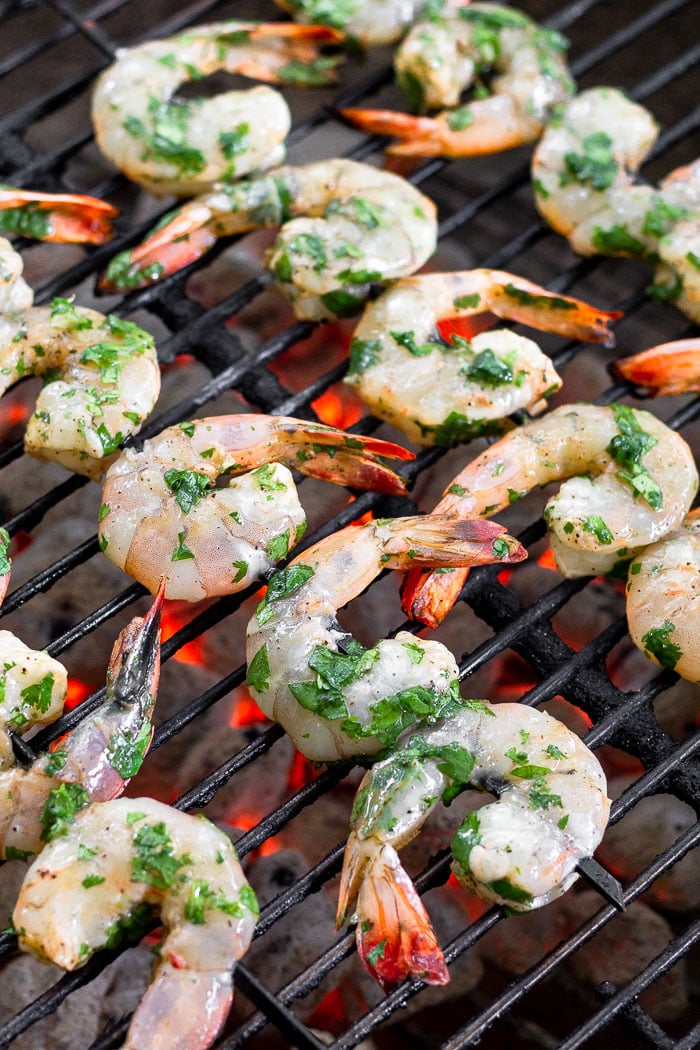 Raw shrimp on skewers on a grill.