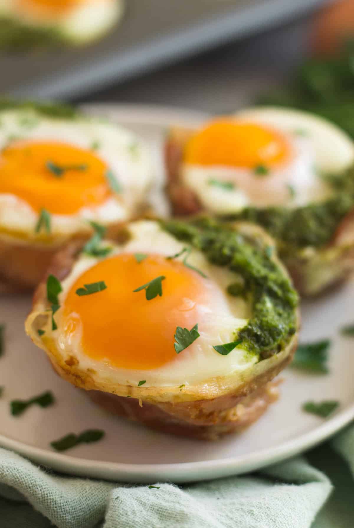 Close up of 3 prosciutto egg cups on a white plate