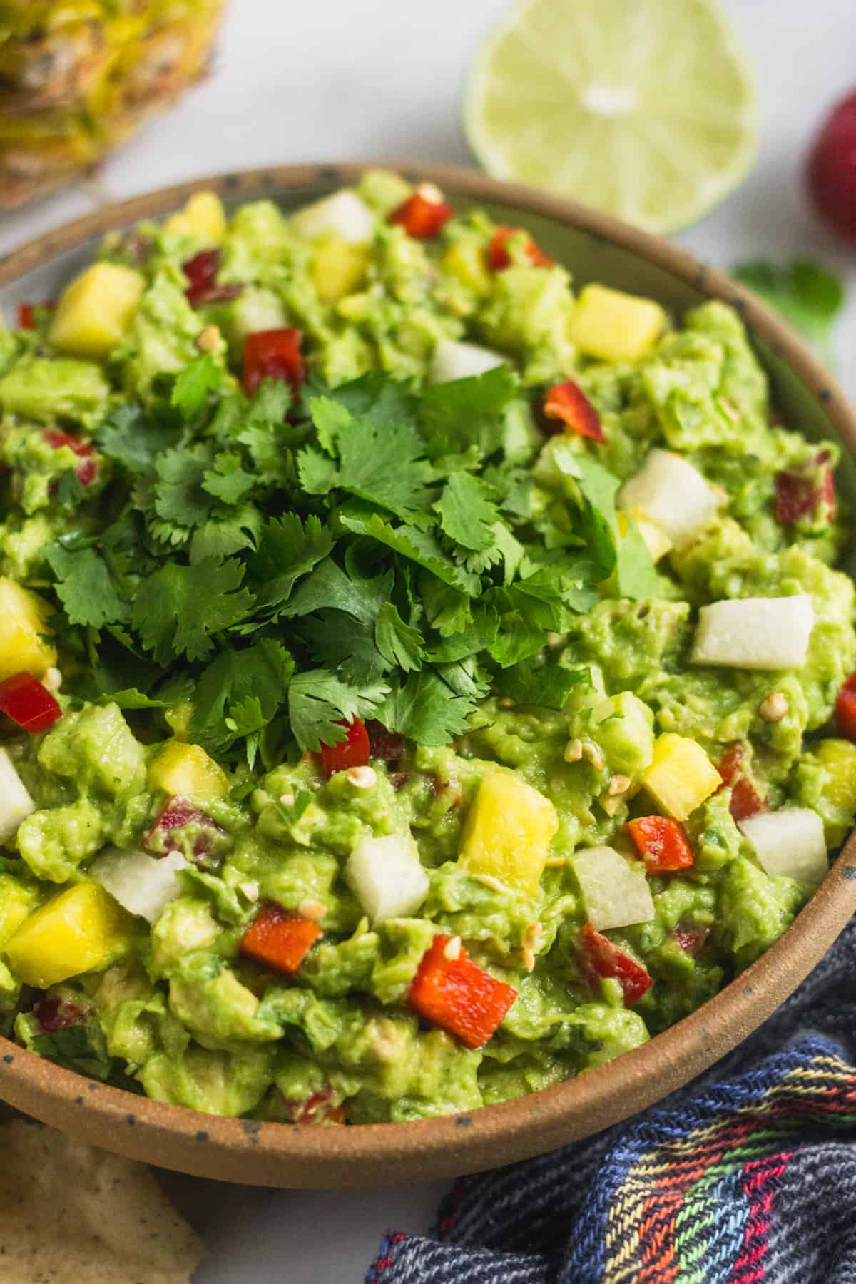 Close up of a bowl filed with spicy pineapple jicama guacamole topped with fresh cilantro