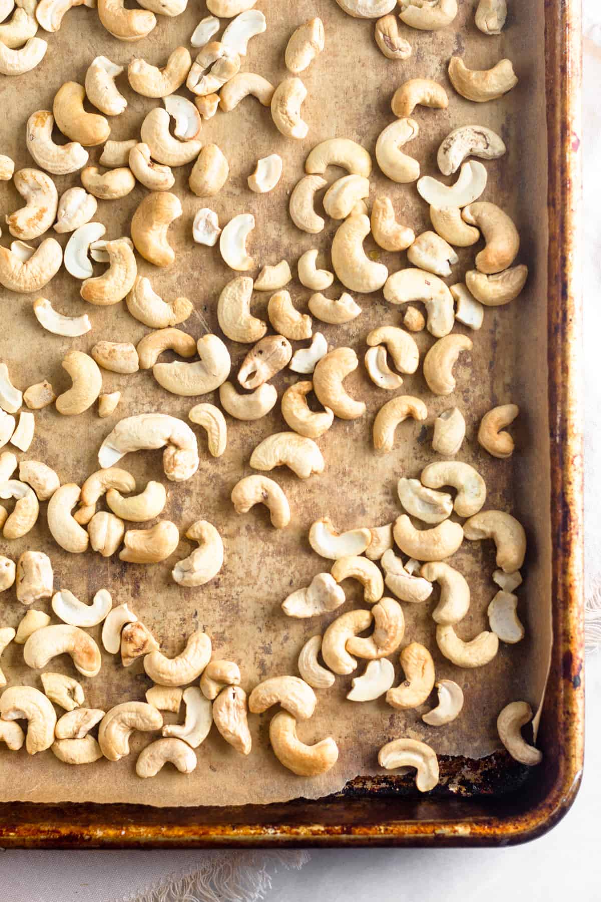 Baking sheet lined with parchment paper and full of roasted cashews