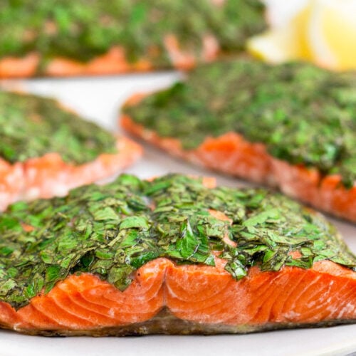 Plate filled with filets of herb grilled salmon and lemon wedges.