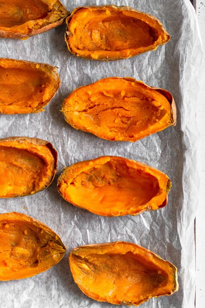 Sweet potatoes cut in half lengthwise with the inside flesh scooped out.