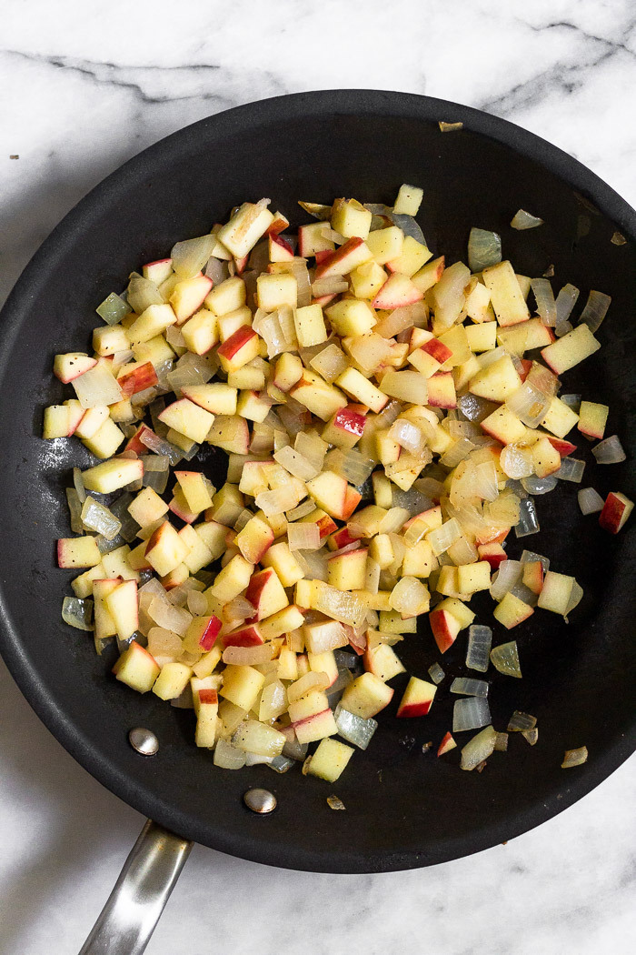 Saute pan filled with sautéed apples and onions.