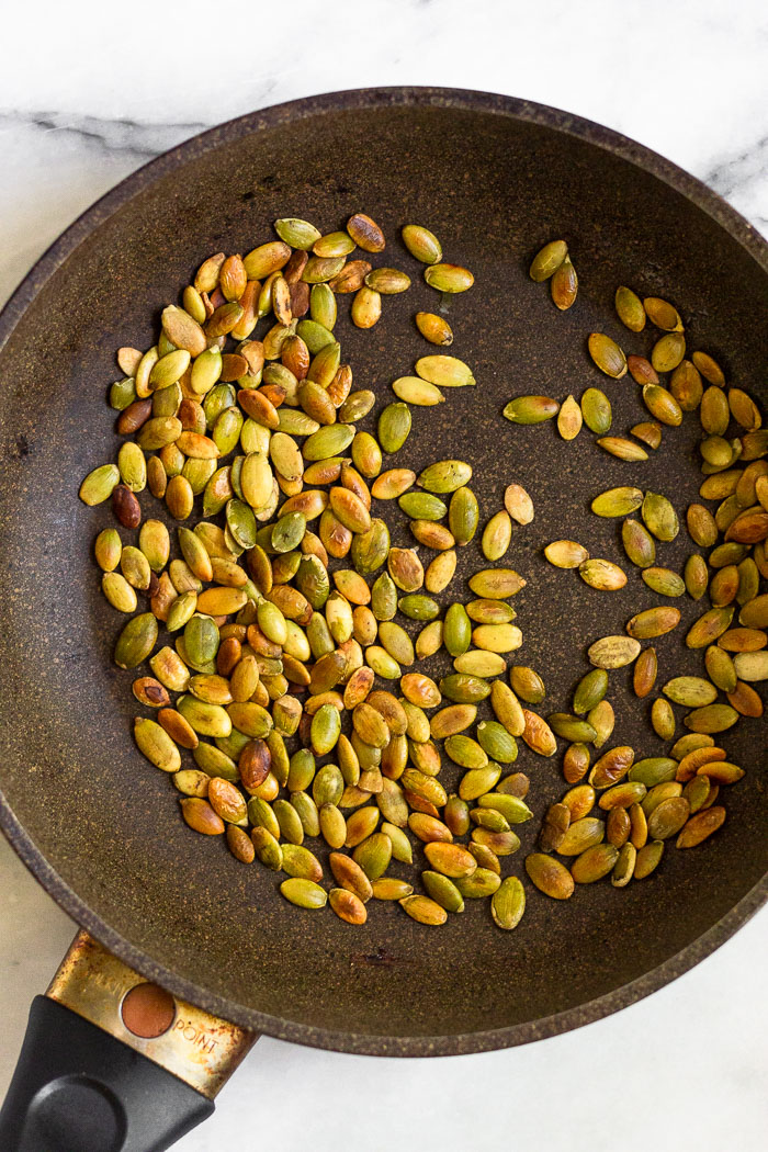 Small saute pan filled with toasted pumpkin seeds.