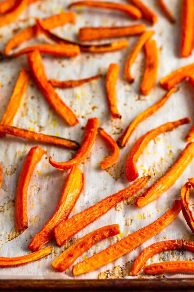 Baked carrot fries on a baking sheet lined with parchment paper.