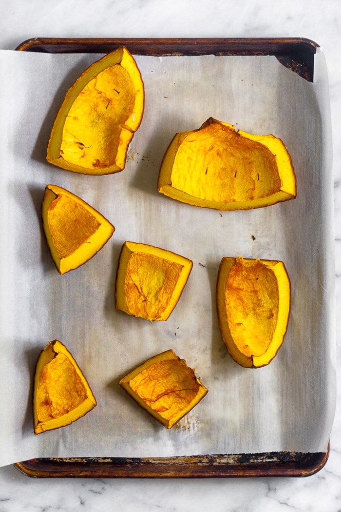 Baking sheet with big pieces of roasted pumpkin on it.