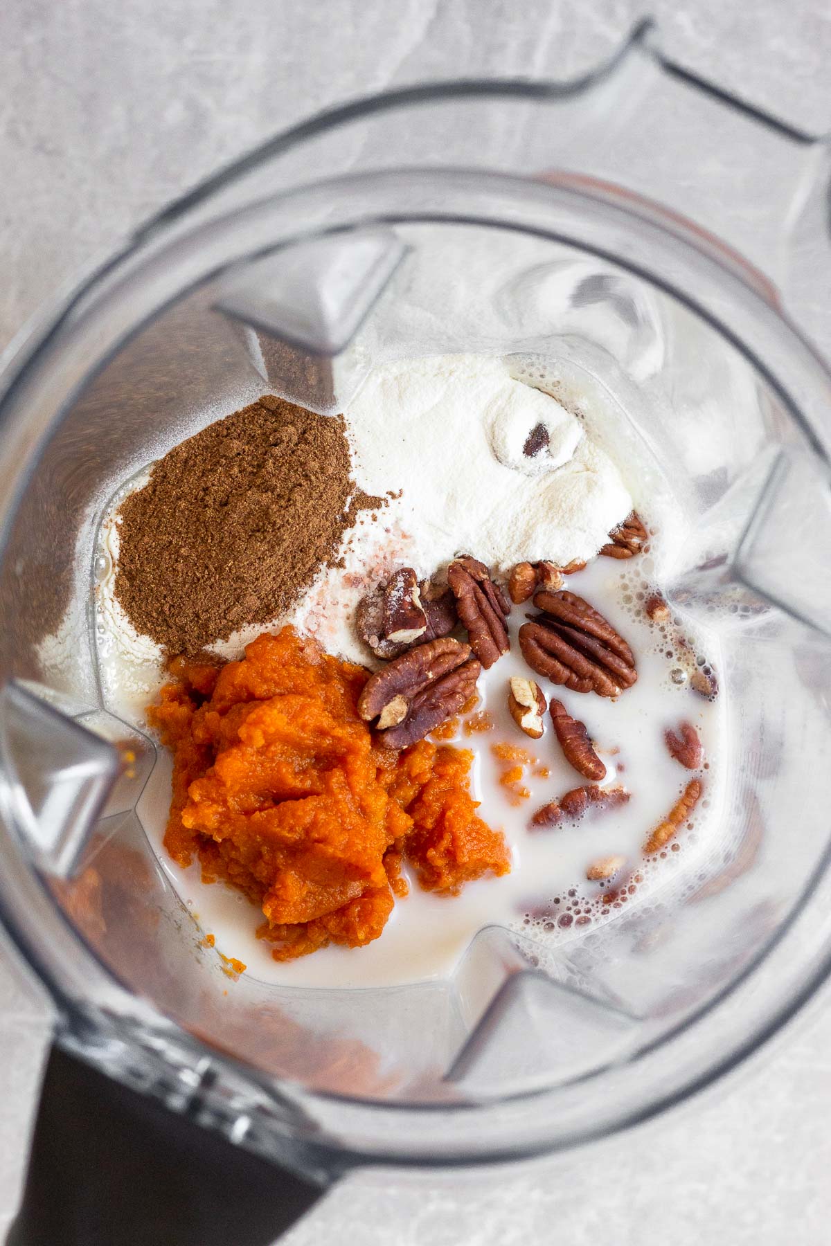 Blender filled with milk, spices, collagen, and pecans.