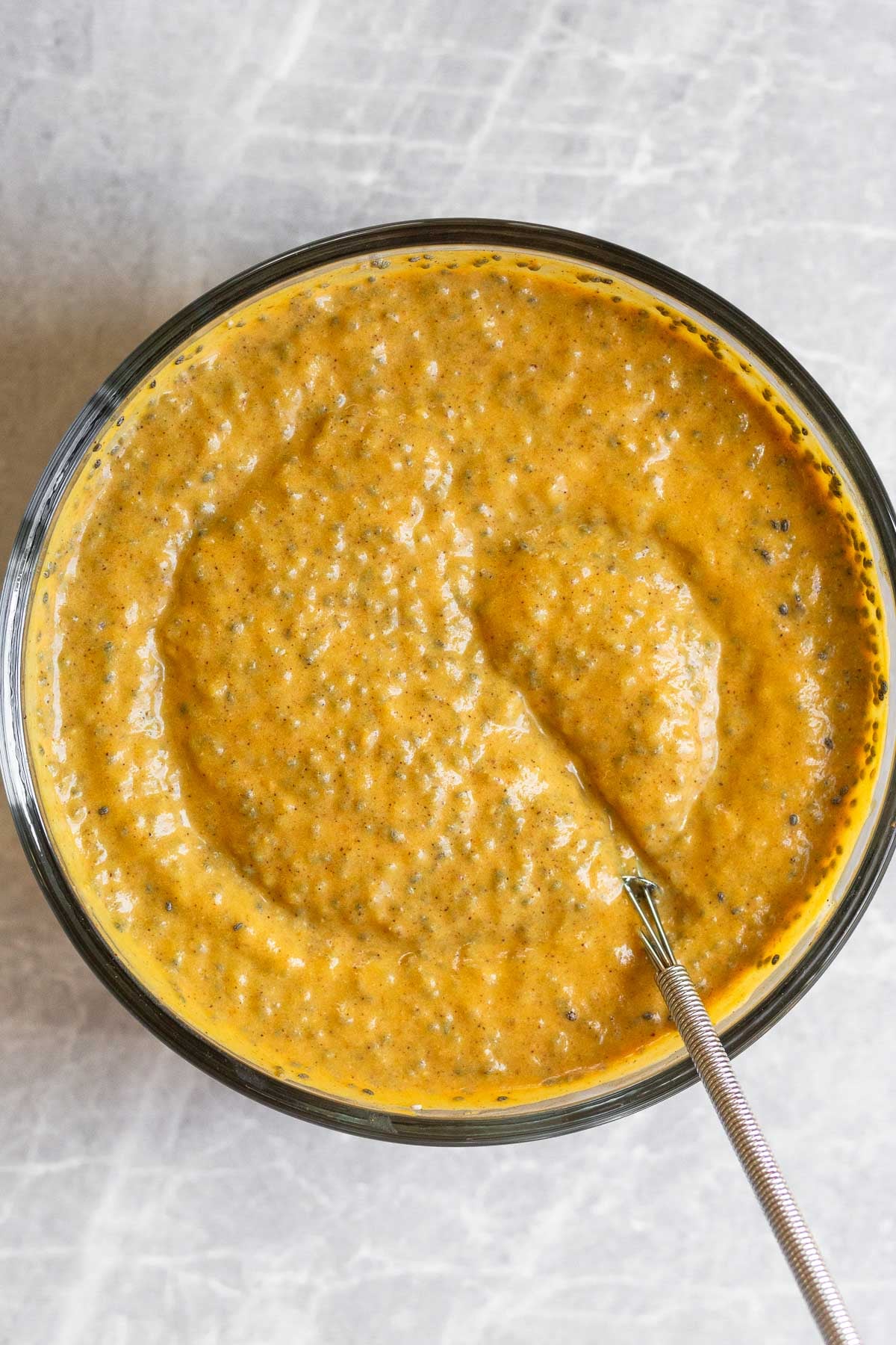 Bowl of a pumpkin mixture with chia seeds mixed in before it gels.