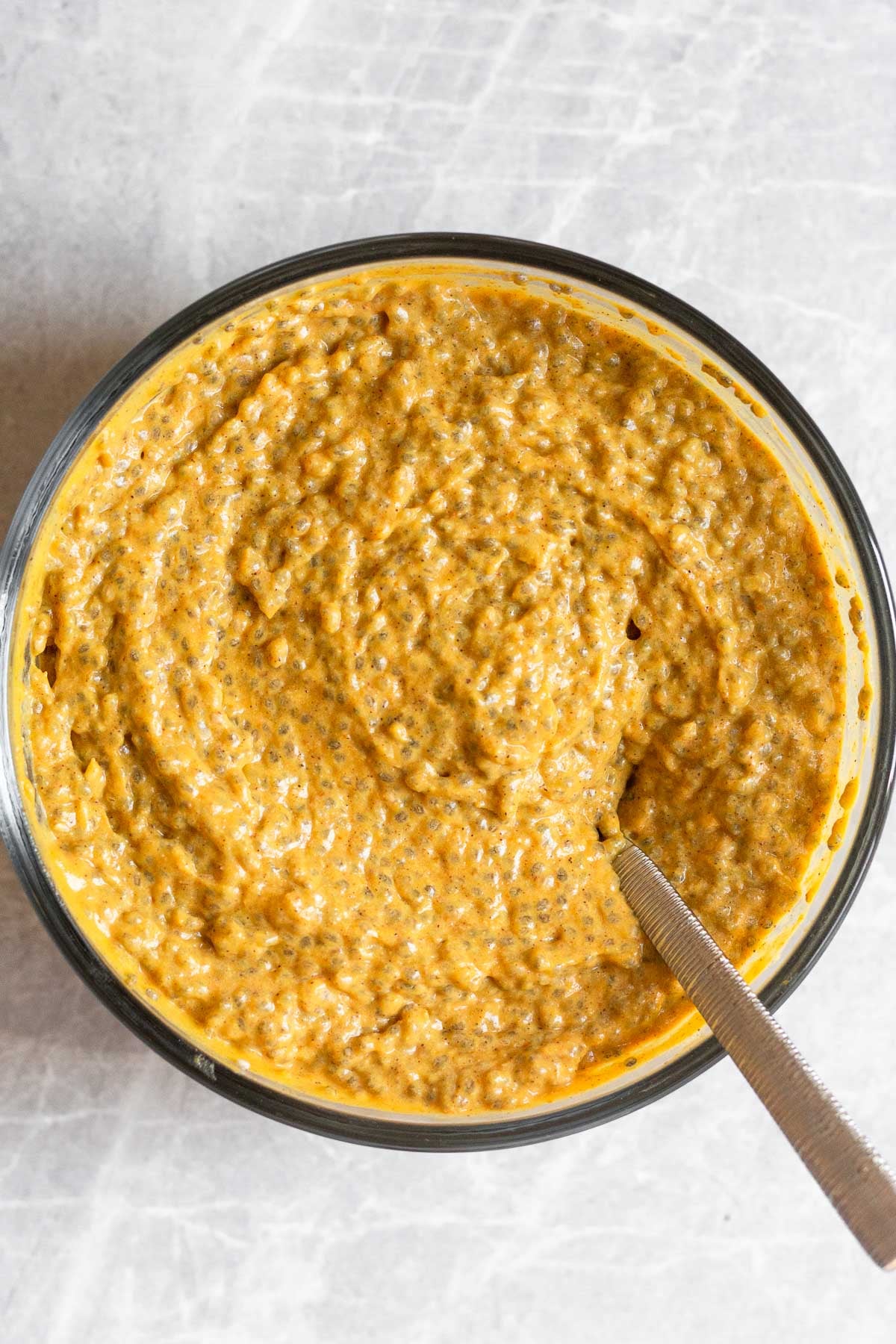 Pumpkin spice chia pudding in large bowl with a spoon in it.