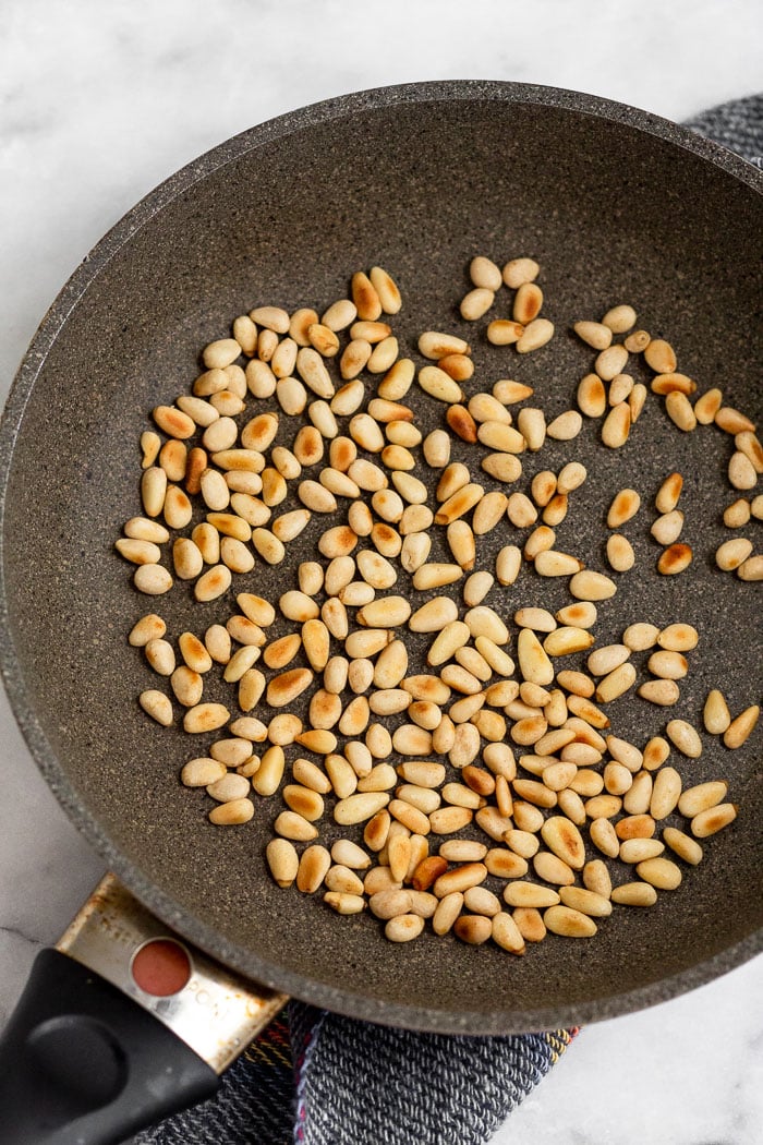 A small skillet filled with toasted pine nuts.
