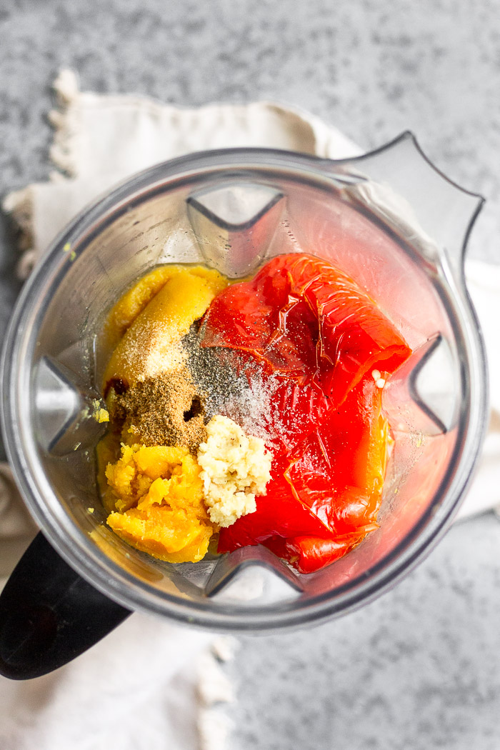 Blender filled with broth, roasted squash and red peppers, fresh grated ginger, and spices.