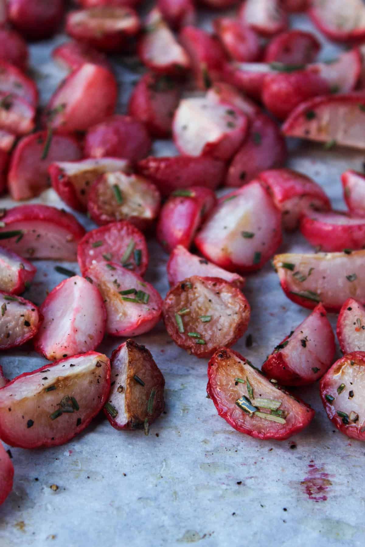 A bunch of rosemary roasted radishes on a baking sheet lined with parchment paper.