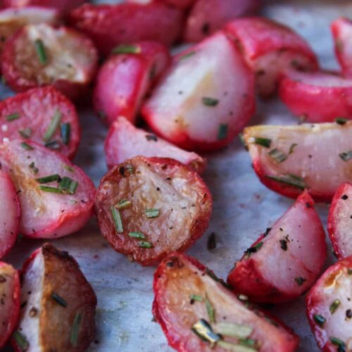 Close up on garlic roasted radishes tossed with fresh rosemary.