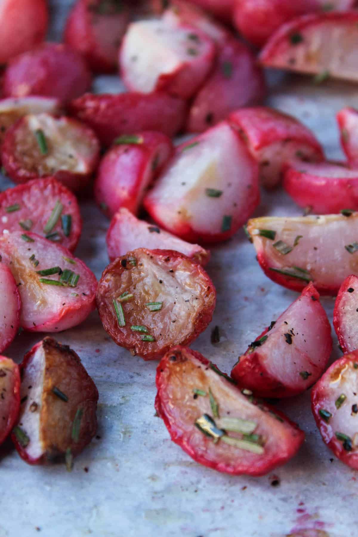 Close up on garlic roasted radishes tossed with fresh rosemary.