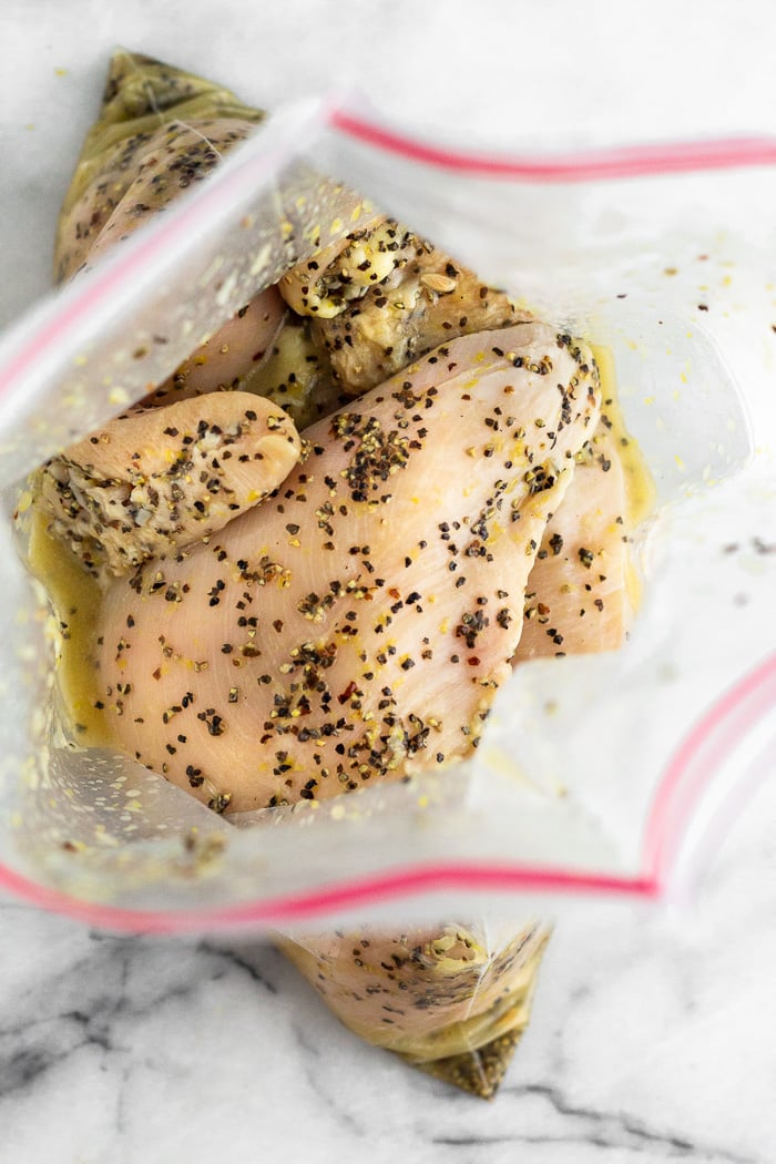 A bag of raw chicken marinading with lemon juice and pepper.
