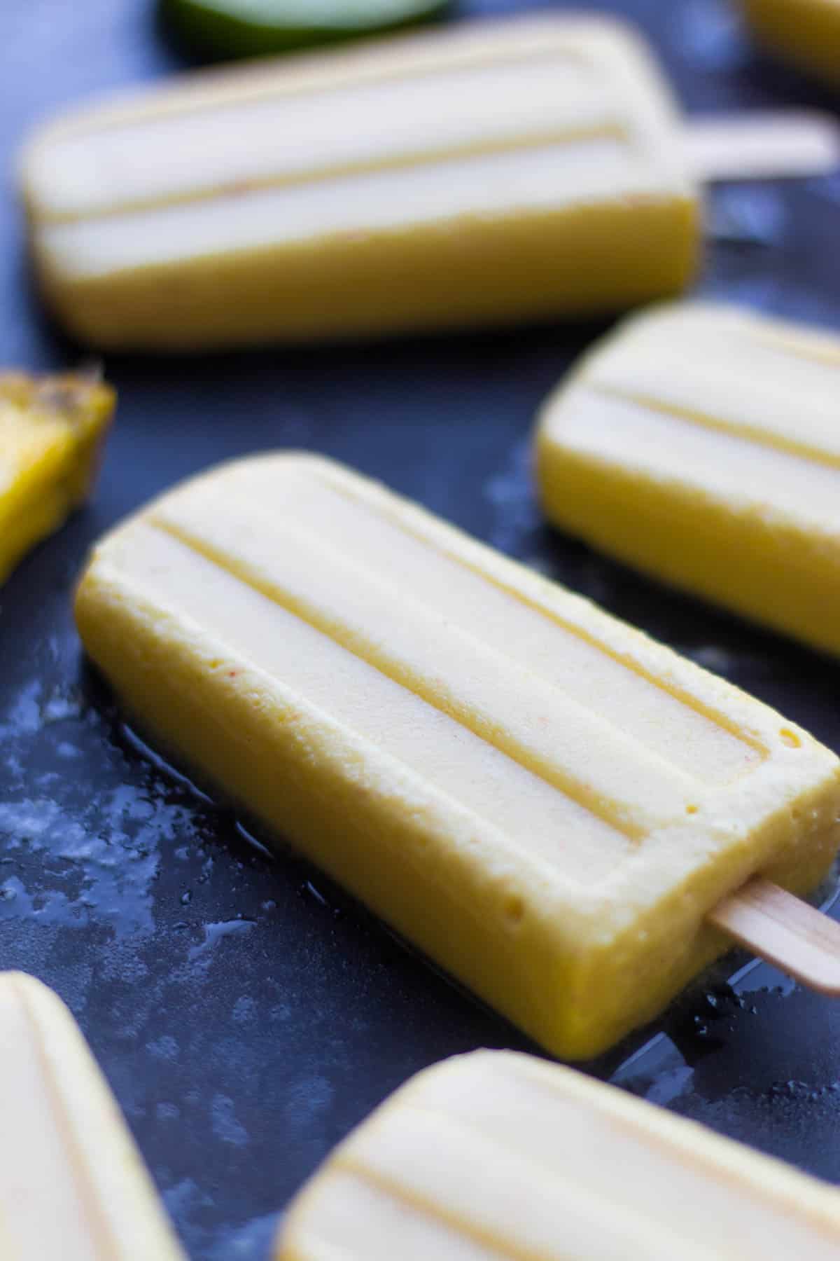 4 ingredient Pineapple Popsicles make an easy and healthy summertime treat. They are vegan, paleo, and sweetener free! - Eat the Gains