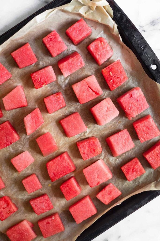 Baking sheet with cubed watermelon on it.