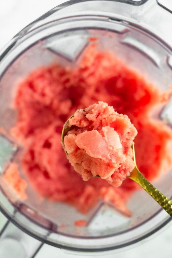 A spoonful of watermelon lime sorbet overtop a blender with more sorbet in it.