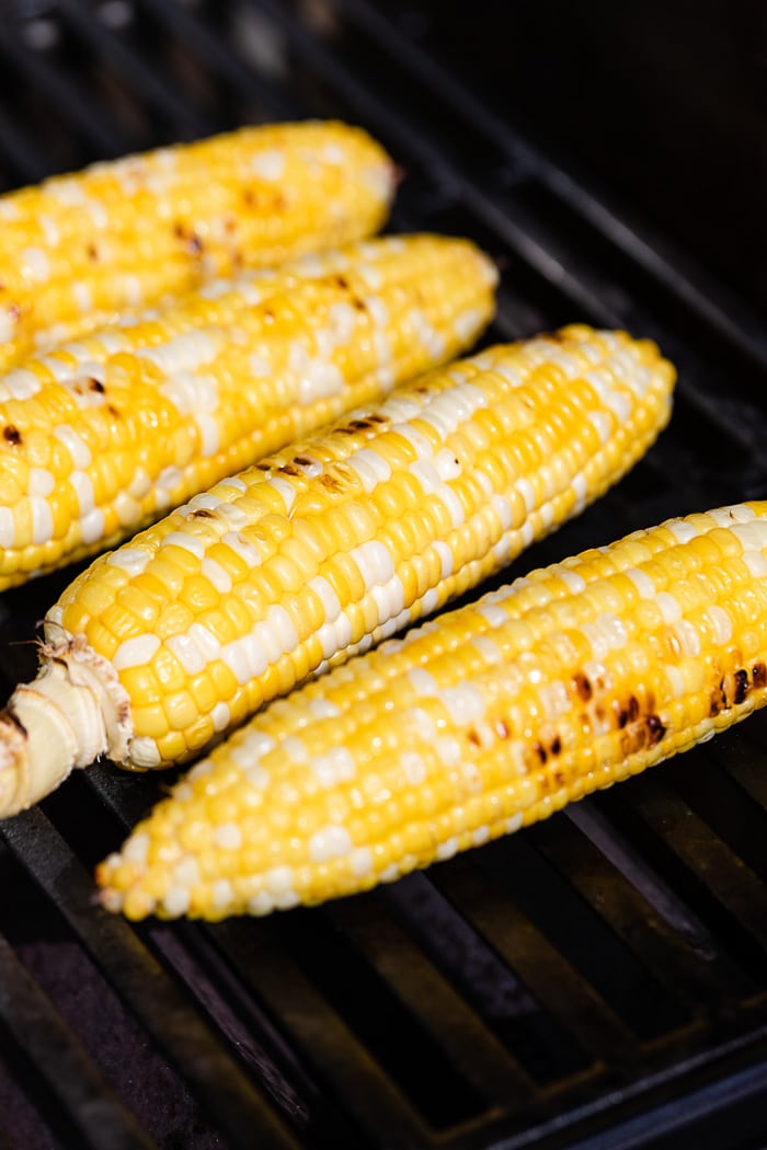 Four pieces of corn on the cob on the grill cooking.