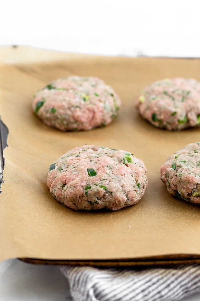 Ranch burgers before they are cooked on a parchment paper lined baking sheet.
