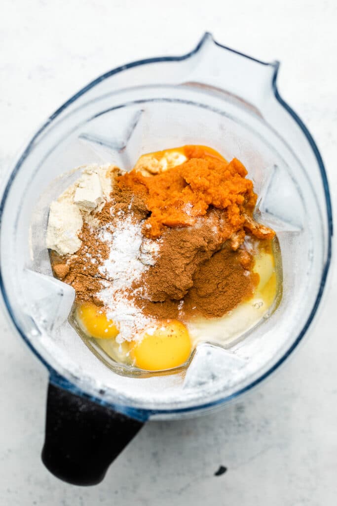 Blender filled with oats, eggs, pumpkin puree, spices, and baking soda and powder.