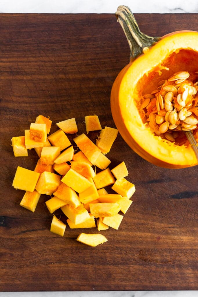 Half a sugar pumpkin roughly chopped with the other half intact next to it.