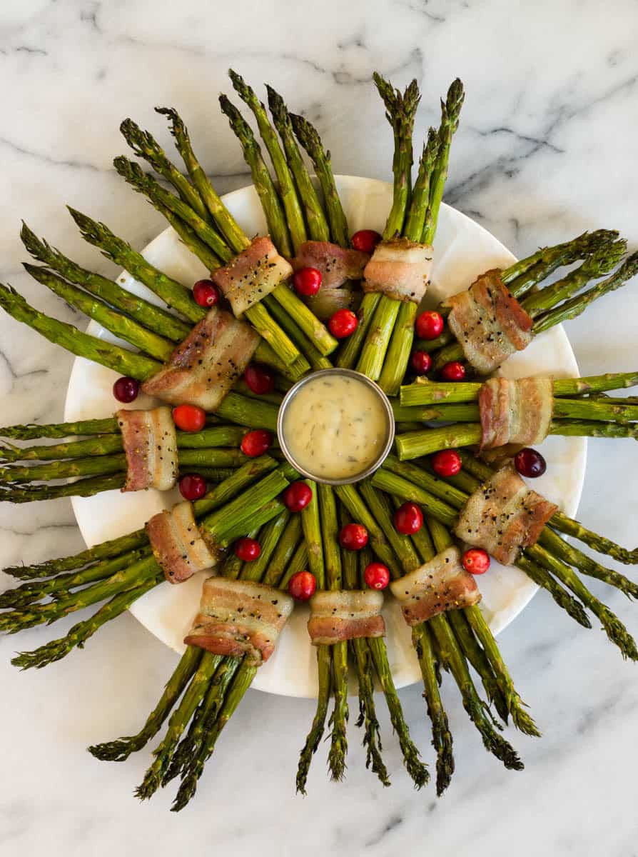 Fun and festive paleo & Whole30 dish with only a few ingredients, a Bacon Wrapped Asparagus Wreath make the perfect appetizer or side at holiday gatherings! - Eat the Gains