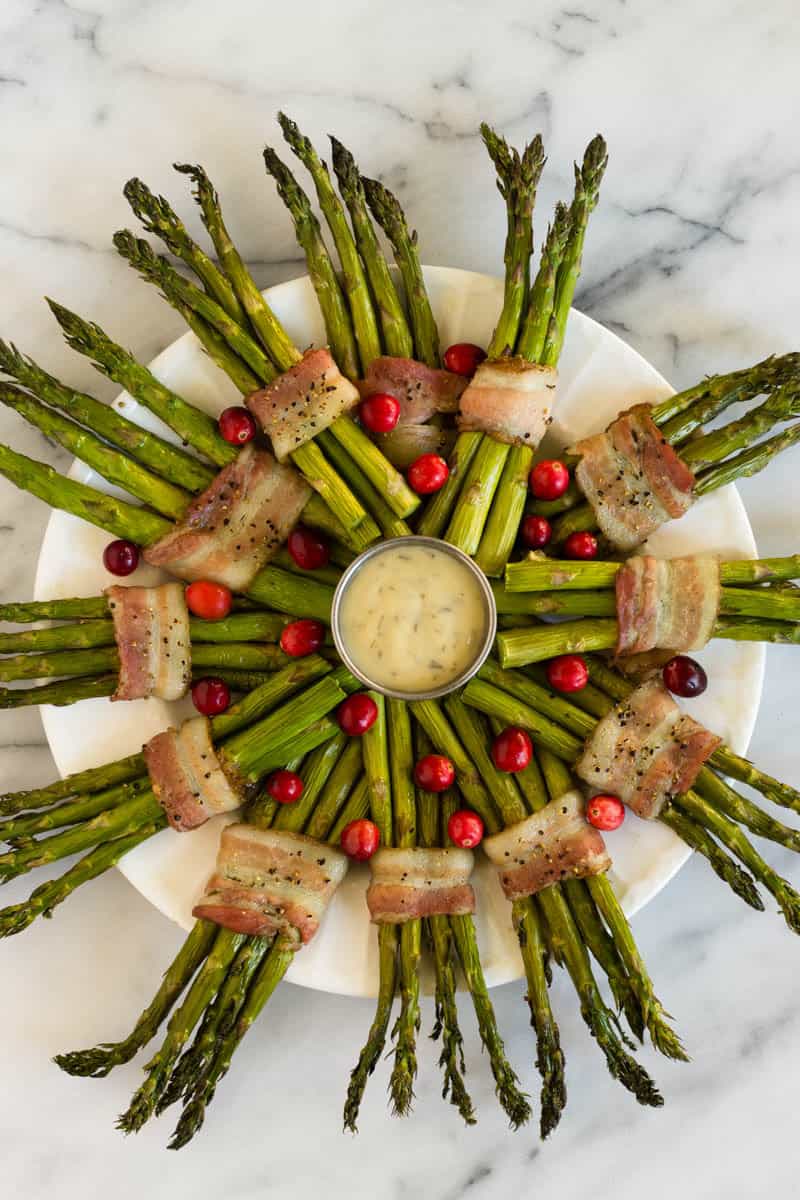 Fun and festive paleo & Whole30 dish with only a few ingredients, a Bacon Wrapped Asparagus Wreath make the perfect appetizer or side at holiday gatherings! - Eat the Gains