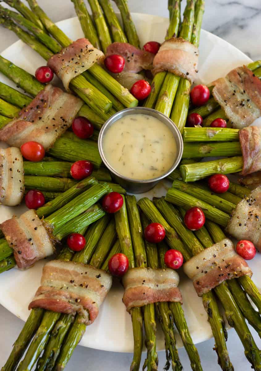 Fun and festive paleo & Whole30 dish with only a few ingredients, a Bacon Wrapped Asparagus Wreath make the perfect appetizer or side at holiday gatherings! - Eat the Gains