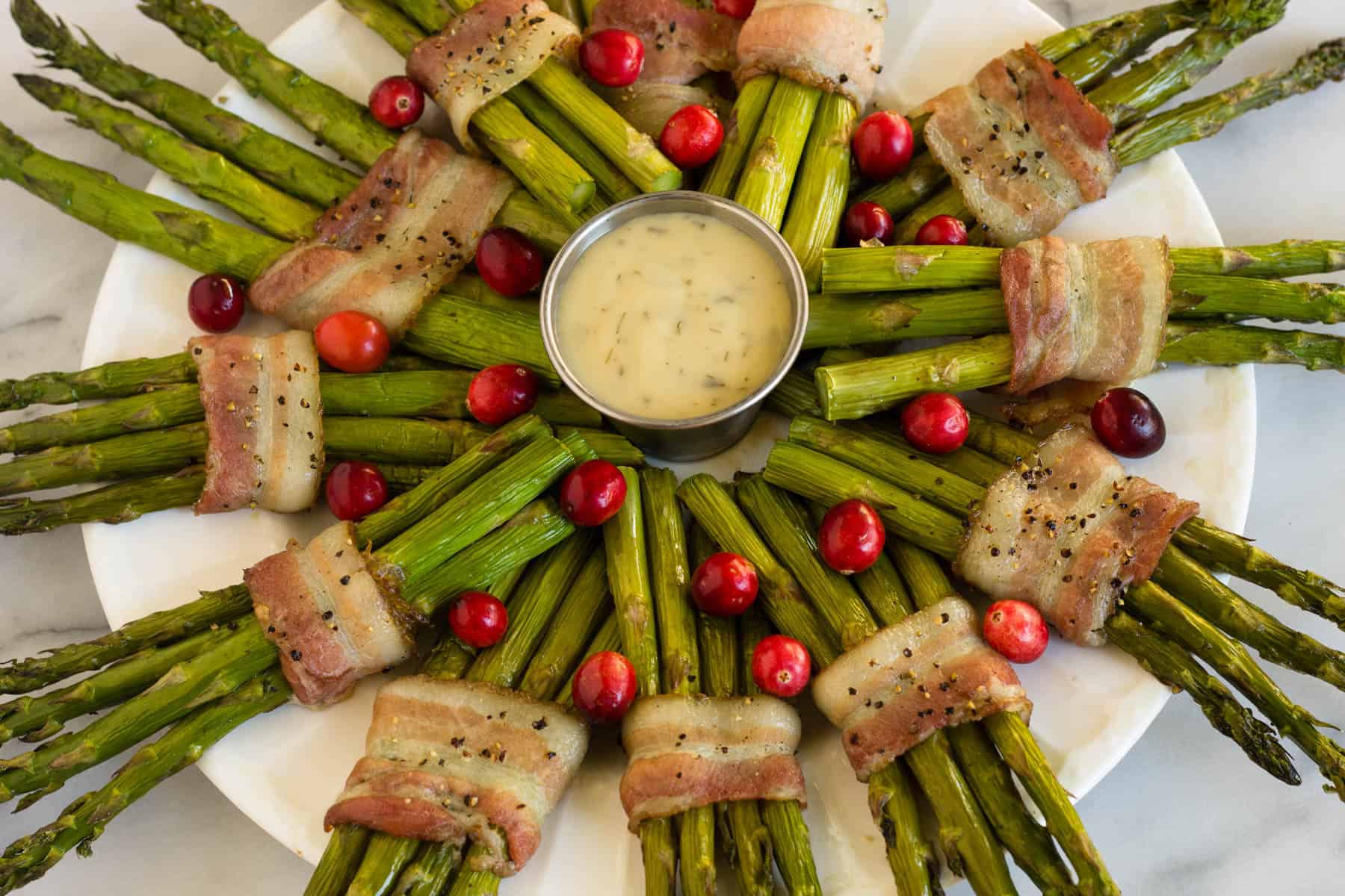 Fun and festive paleo & Whole30 dish with only a few ingredients, a Bacon Wrapped Asparagus Wreath make the perfect appetizer or side at holiday gatherings! - Eat the Gains