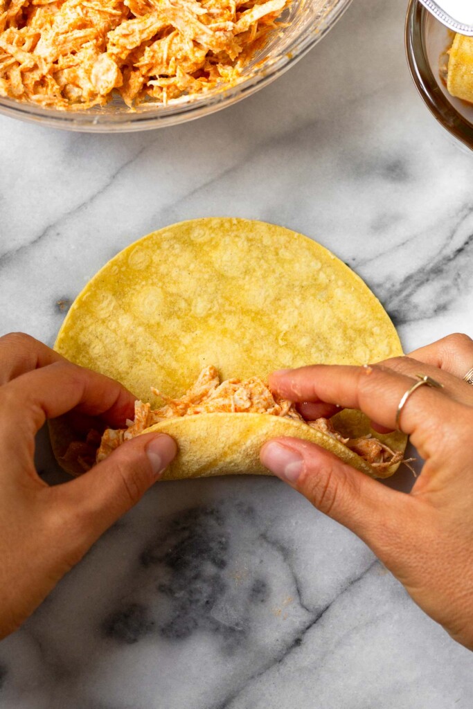 Chicken enchilada being rolled up.