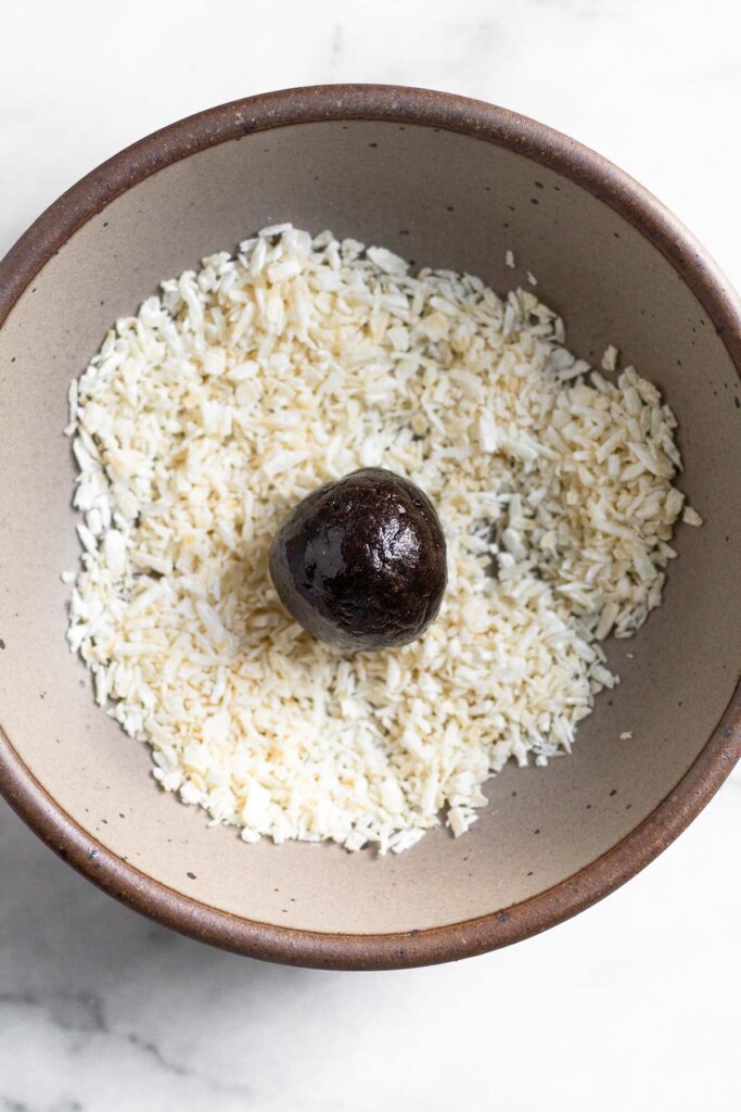 A small bowl of shredded coconut with a chocolate protein bowl in it.