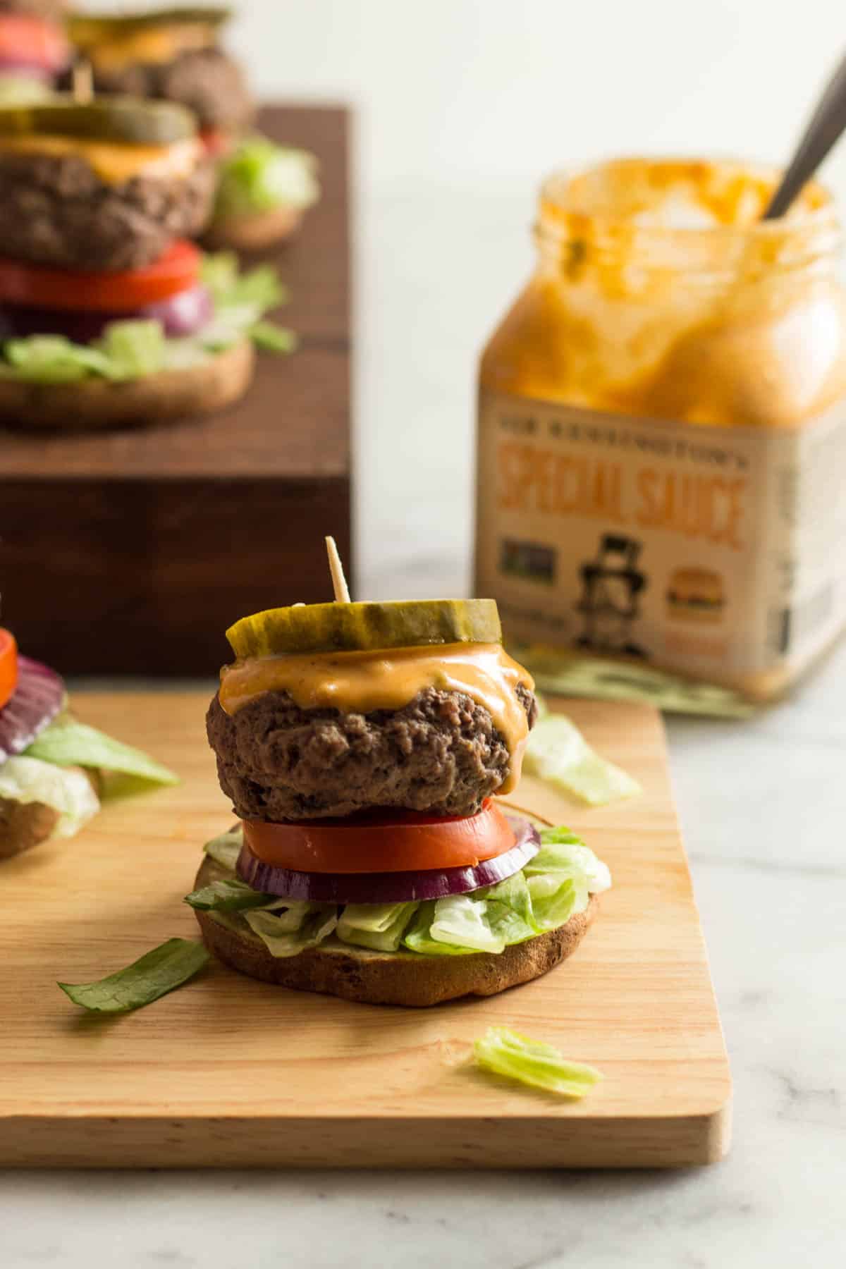 Burger slider on sweet potato bun with a jar of special sauce and more sliders in the background