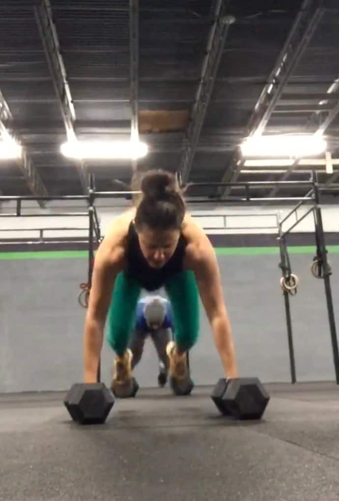 girl holding dumbbells doing a burpee