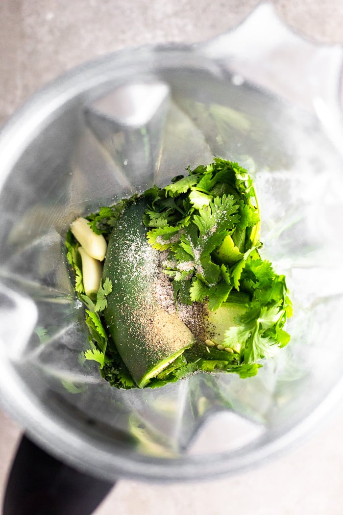 Blender filled with herbs, garlic, jalapeño, and spices.