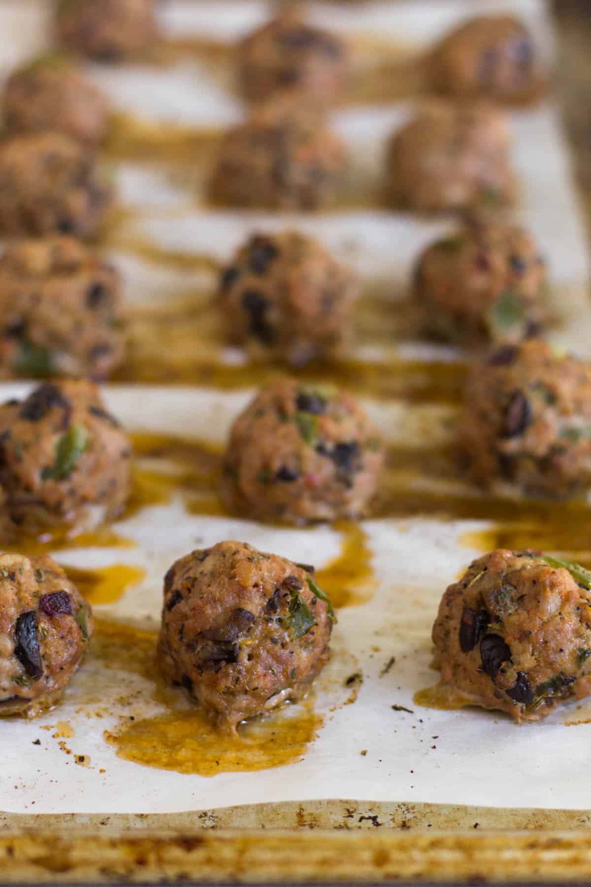 Baking sheet of cooked supreme pizza meatballs