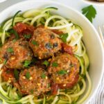 Bowl of supreme pizza meatballs with sauce over zucchini noodles