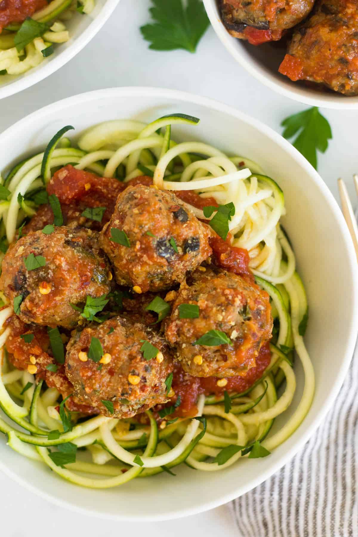 Bowl of supreme pizza meatballs with sauce over zucchini noodles