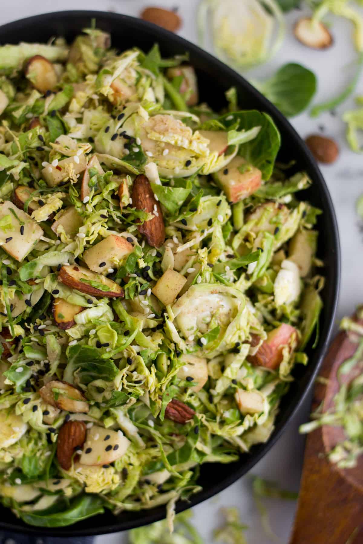 Close up of a black bowl with apple & shaved brussels sprouts salad