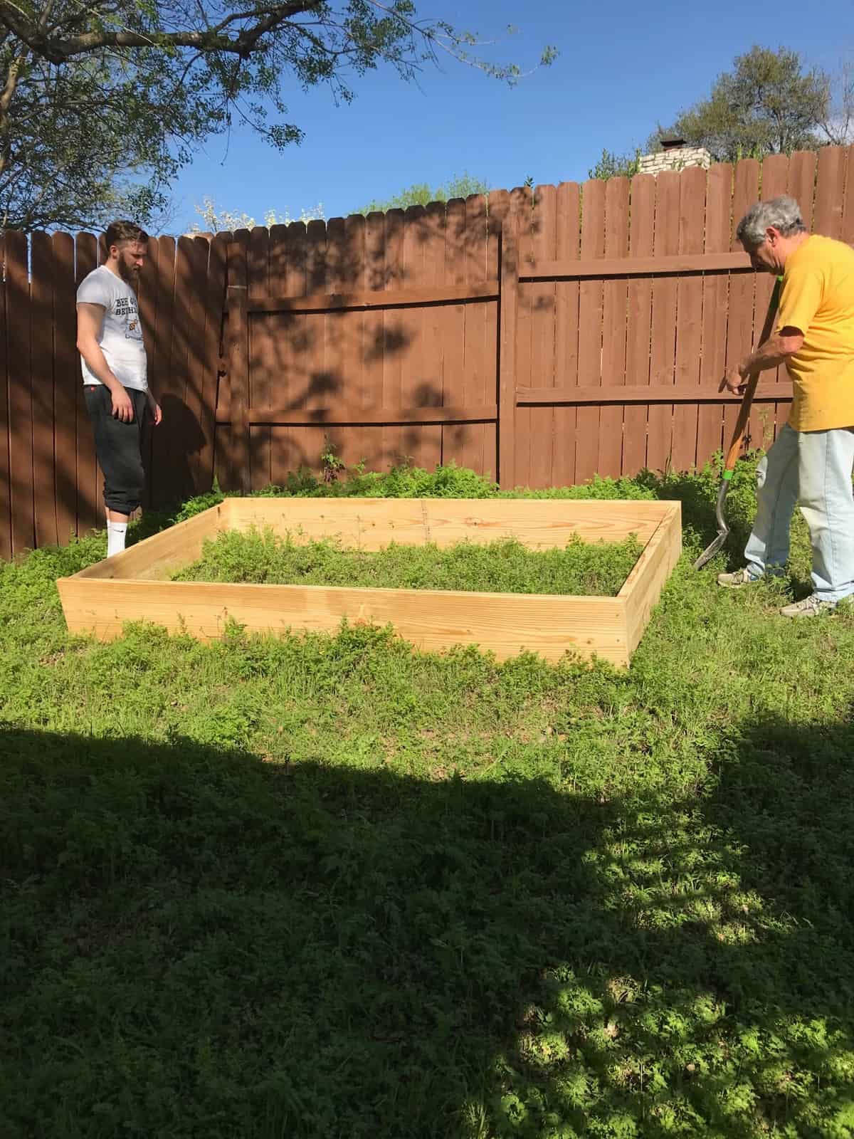 Two guys standing next to a raised bed before it is installed