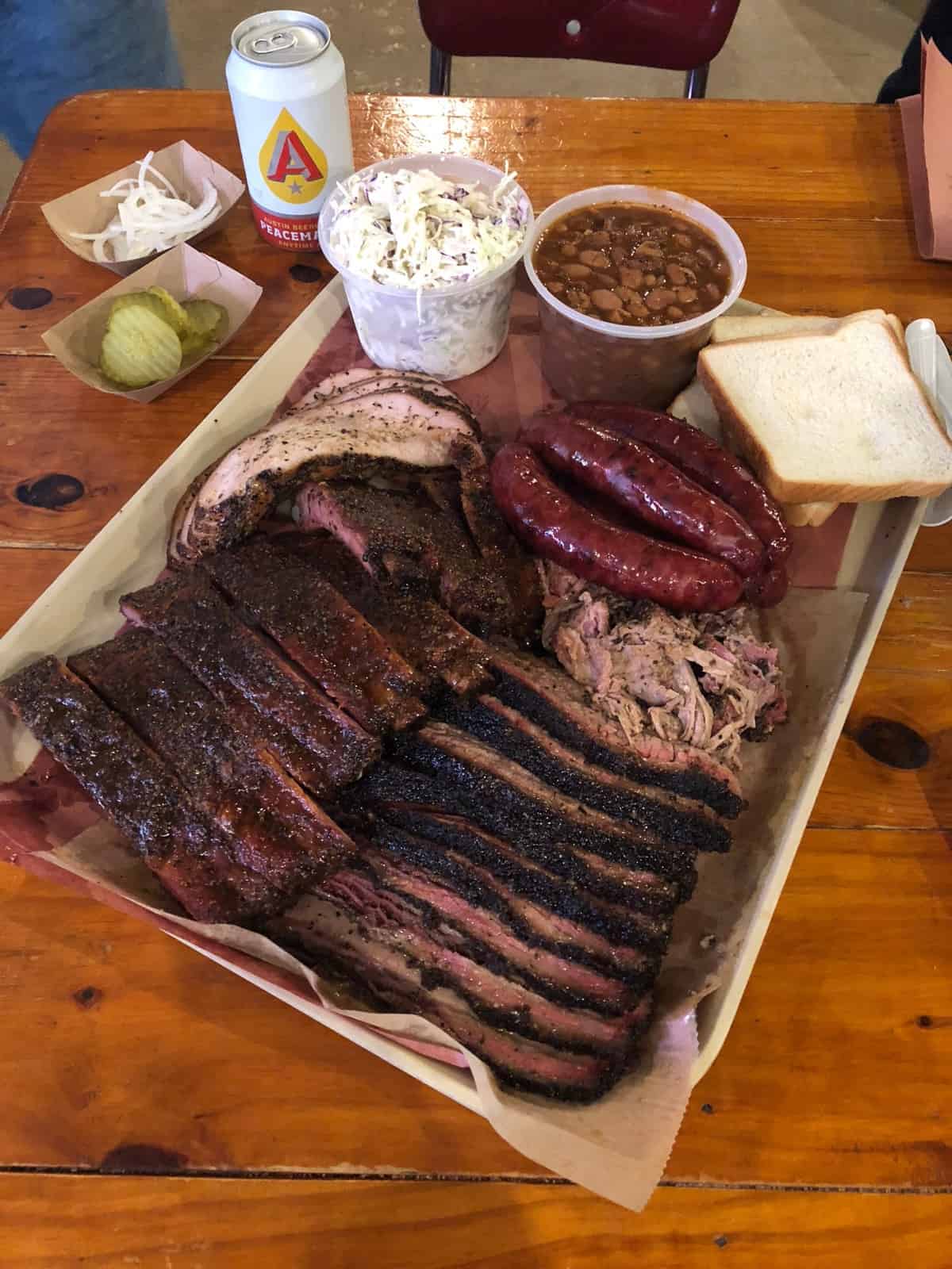 Huge pile of BBQ on a baking sheet - brisket, pulled pork, sausage, beans, coleslaw, turkey, and ribs,