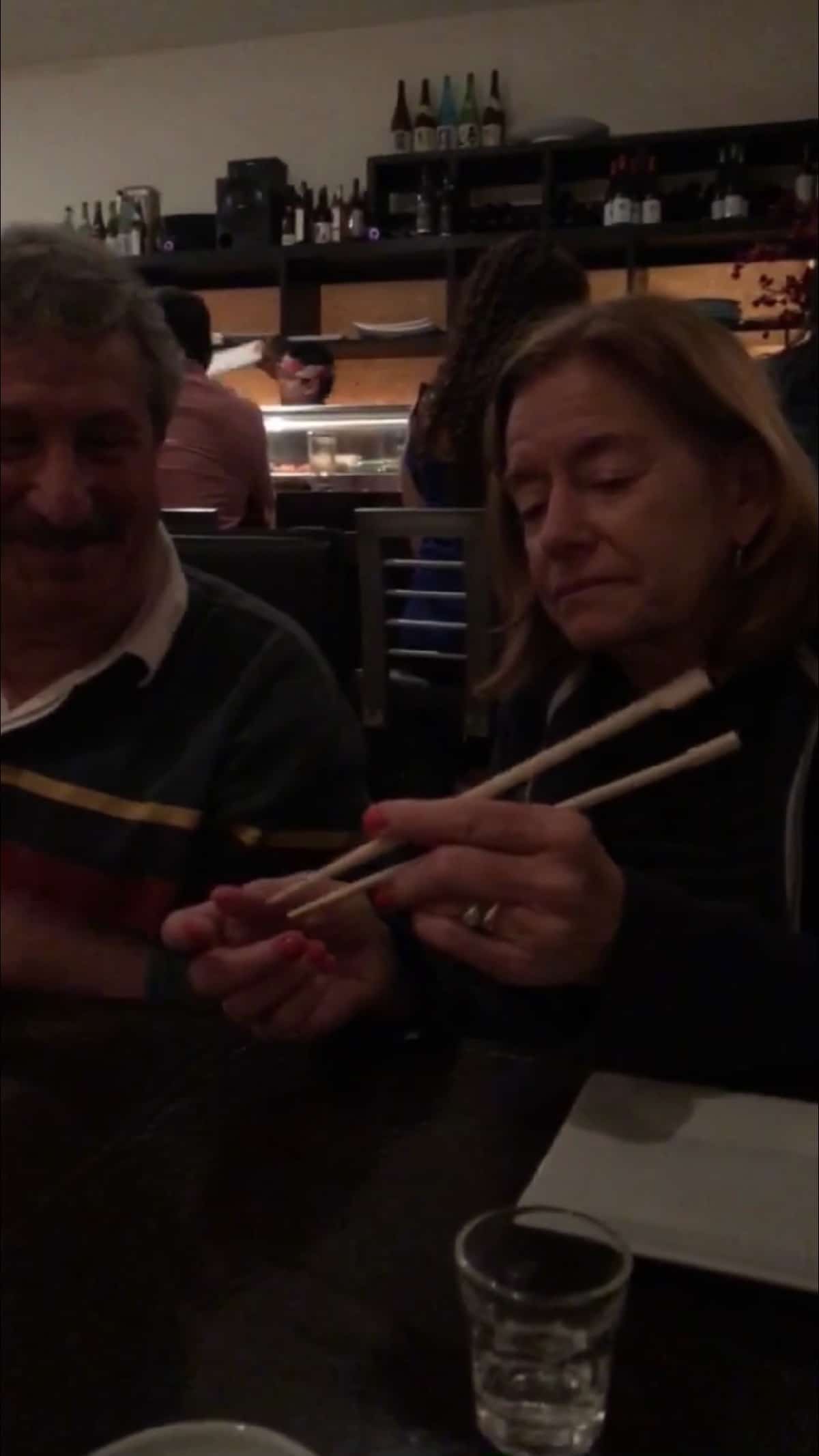 Lady showing a man how to use chopsticks